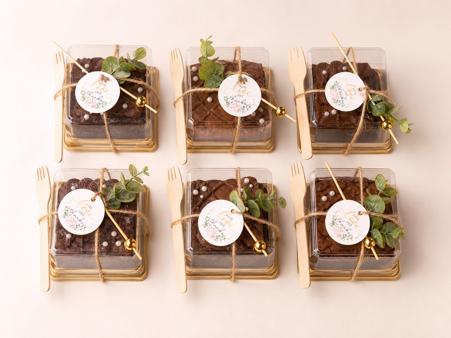 Six real BrowniBop brownies, each presented in a clear individual favor pot with a gold base, twine, greenery and a wooden fork
